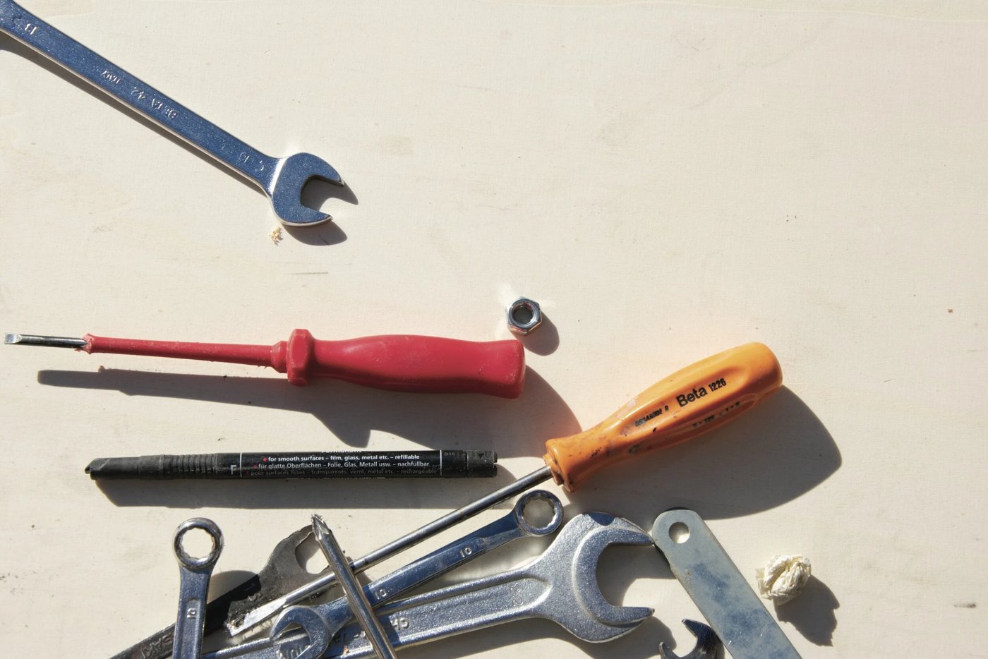 Wrenches, screwdrivers and a nut scattered on a light work surface
